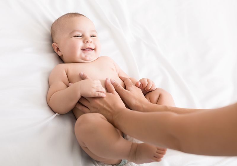 Bebé que le están dando masaje abdominal para los cólicos infantiles.